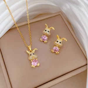 Golden rabbit jewelry set with pink crystal and diamonds on white silk fabric