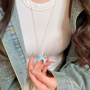 Détail du collier pendentif poney bleu porté par un mannequin en gilet blanc
