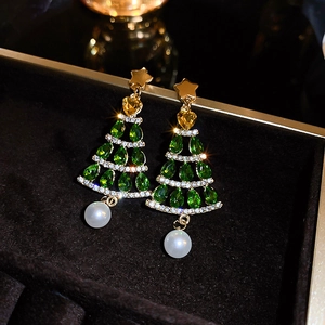 Christmas tree drop earrings with green zircons, gold stars, and pearls on black velvet