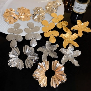 Macro shot of chunky gold and silver floral fan-shaped metal earrings with hammered texture