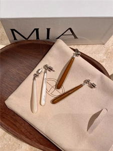 Close-up of elegant teardrop earrings in white pearl and amber resin finishes
