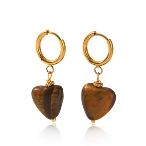 Macro shot of gold hoop earrings with heart-shaped tiger eye stone pendants and tassels