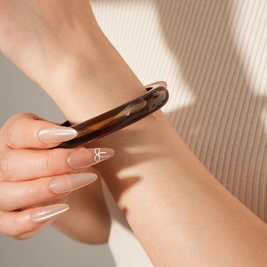 Detail of brown tortoiseshell resin bangle on wrist with elegant natural lighting