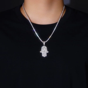 Close-up of a silver Hamsa Hand pendant with star motif on a tennis chain