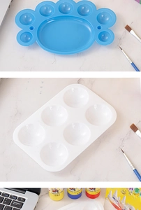 Close-up of blue cat paw and white 6-well plastic mixing palettes for painting