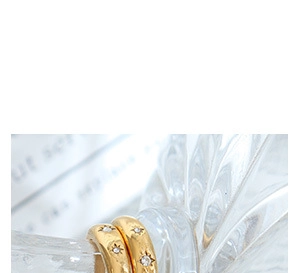 Detailed macro view of gold starburst earrings with zircon on fluted glass edge