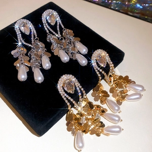 Detail view of gold and silver tassel earrings with crystals and drop pearls on velvet
