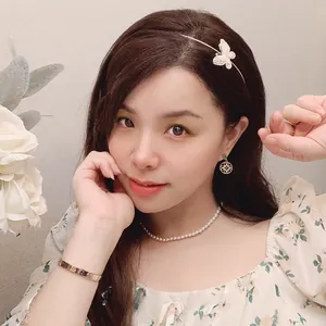 Dettaglio dell'elegante cerchietto a farfalla con strass e collana di perle su modella