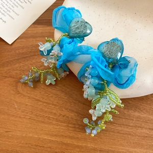Detailed shot of handmade blue fabric flower earrings with crystal heart accents