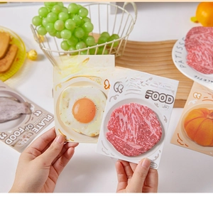 Detailed view of realistic fried egg and beef food-shaped sticky notes on a table