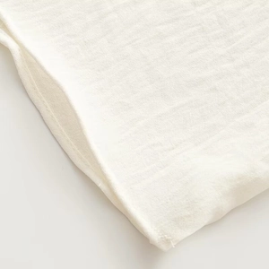 Close-up of white cotton linen fabric showing detailed texture and stitching quality