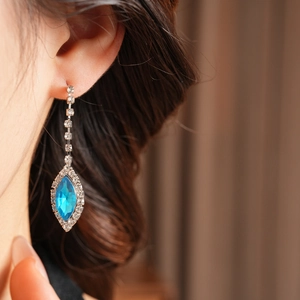 Close-up of blue teardrop earring with crystal fringe on model showing elegant details