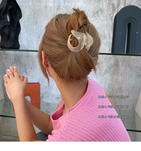 Vue détaillée d'une pince à cheveux beige translucide fixant un chignon de queue de cheval