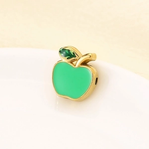 Macro view of a green enamel apple pendant with gold metal edges for jewelry making