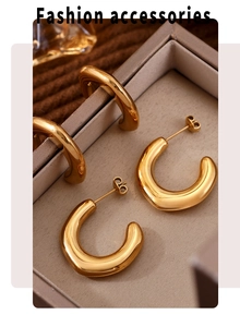 Detailed close-up of gold C-shaped chunky hoop earrings with butterfly backings in a box