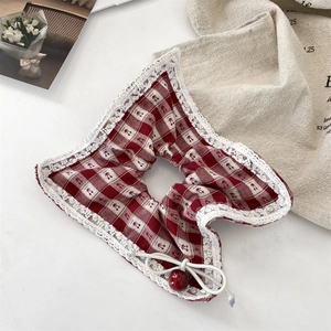 Detail of a red gingham scrunchie with delicate white lace trim and cherry charm