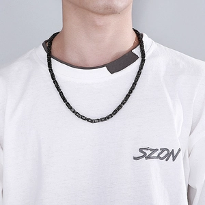 Detail of a bold black imperial chain necklace in woven titanium steel on a male model neck