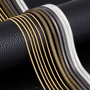 Macro detail of various color snake chains including gold and silver on black leather