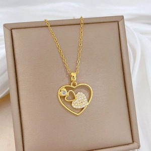 Close-up of golden dual heart necklace with pavé zircon inlay in a jewelry box
