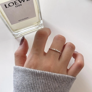 Detail of minimalist wavy 925 silver ring with green cubic zirconia stones on model hand