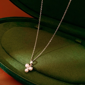 Detail of three white pearls and zircon pendant on a silver chain in a green velvet box