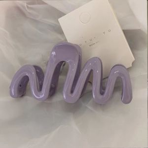 Detailed view of a purple wavy hair claw clip on a white branded display card