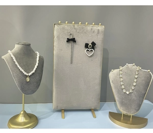 Detail view of gold metal jewelry stands with grey velvet boards for necklace and earrings