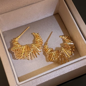 Close-up of gold-plated twisted coil earrings displayed in a luxury jewelry box