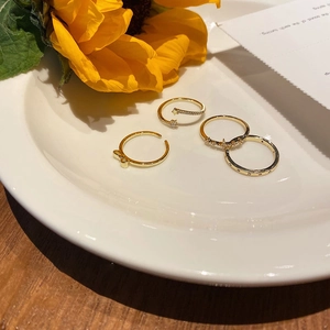 Detail view of four gold-plated bow and star rings arranged in a white ceramic dish