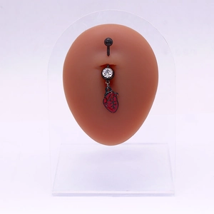Piercing de nombril noir avec pendentif cœur rouge présenté sur un modèle de nombril