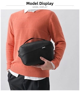 Detail of the black sport bag with a top handle and logo held by a model in orange