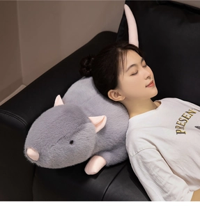 Nahaufnahme einer weichen grauen Maus aus Plüsch mit rosa Ohren auf einem Ledersofa