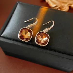 Elegant gold earrings with square amber cubic zirconia on a black jewelry box display