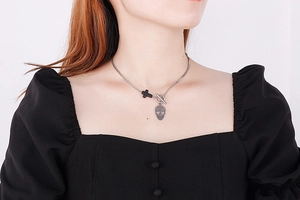 Detailed view of skull and black cross pendants on a silver metal chain with OT buckle