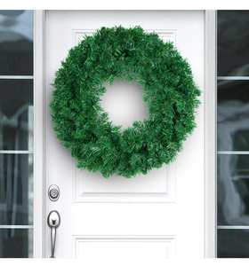 Close-up of a green artificial PVC Christmas wreath hanging on a white windowed door