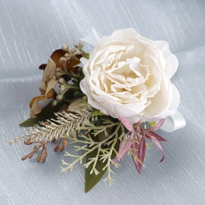 Elegant white silk boutonniere with green leaves and ribbon for wedding ceremony