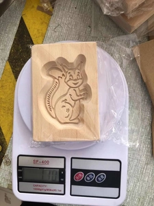 Detail view of rectangular beech wood cookie mold with carved squirrel pattern on a scale