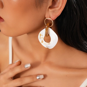 Detailed close-up of bohemian earring with golden hoop and marble resin pendant
