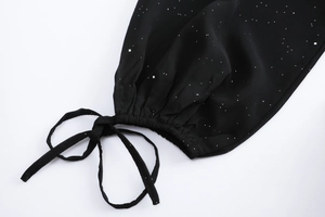 Détail de manche de robe noire à pois avec poignet élastique à volants et nœud de laçage