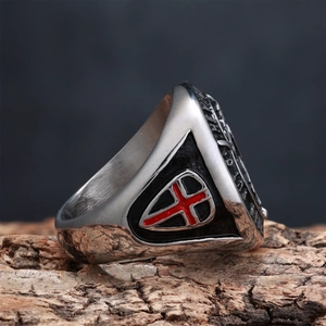 Macro detail of vintage stainless steel shield ring with red cross on tree bark