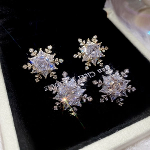 Detailed view of silver snowflake earrings with sparkling cubic zirconia on black velvet