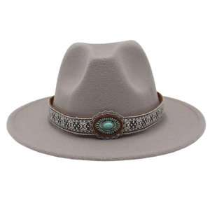 Détail d'un chapeau fedora gris à bord large avec pierre turquoise et bande ethnique tissée