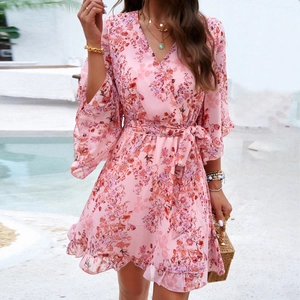 Pink floral chiffon mini dress with V-neck and ruffled sleeves on a model by the pool