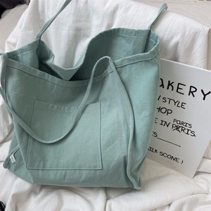 Detailed texture of mint green canvas tote bag with large front pocket on white background