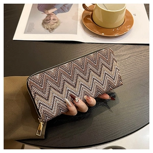 Close-up of brown textured fabric long wallet with gold zipper in a lifestyle setting