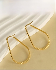 Detailed close-up of gold-plated egg-shaped earrings with unique embossed honeycomb texture