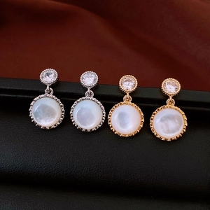 Close-up of vintage resin round drop earrings with sparkling zircon and pearl inlay