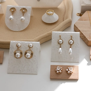 Elegant gold acrylic jewelry display stand with pearl earrings and chain style ring set