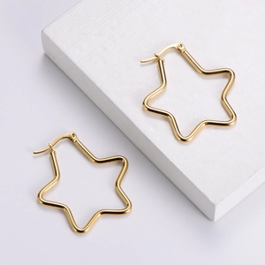 Polished gold stainless steel star earrings on white stone display stand for women
