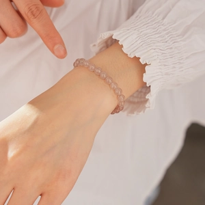 Detailed view of natural strawberry quartz beaded bracelet on model wrist with soft lighting